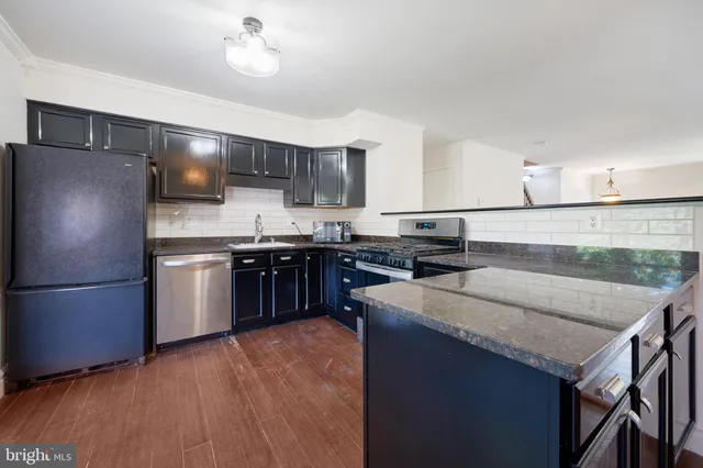 a kitchen with stainless steel appliances granite countertop a refrigerator a sink dishwasher a stove and white countertops with wooden floor