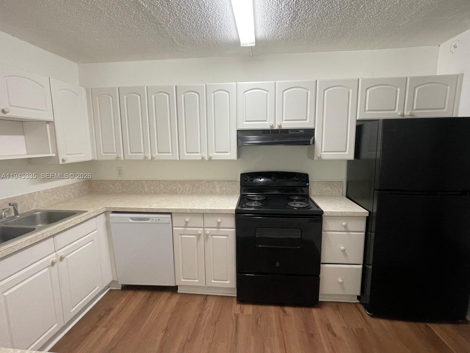 14830 Naranja Lakes Boulevard, Unit A2Q Homestead, FL 33032 - Photo 4 of 8 a kitchen with white cabinets and black appliances