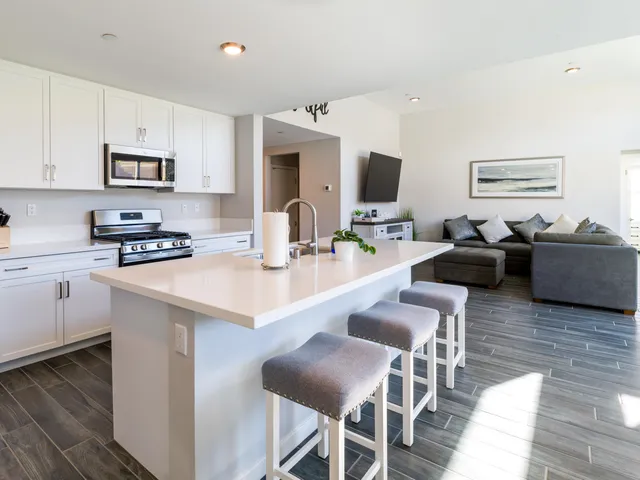 a kitchen with stainless steel appliances kitchen island granite countertop a refrigerator a stove top oven a sink dishwasher and white cabinets with wooden floor