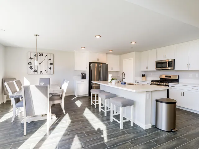 a kitchen with stainless steel appliances granite countertop a stove a sink a microwave a dining table and chairs with wooden floor