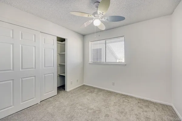 an empty room with windows and fan