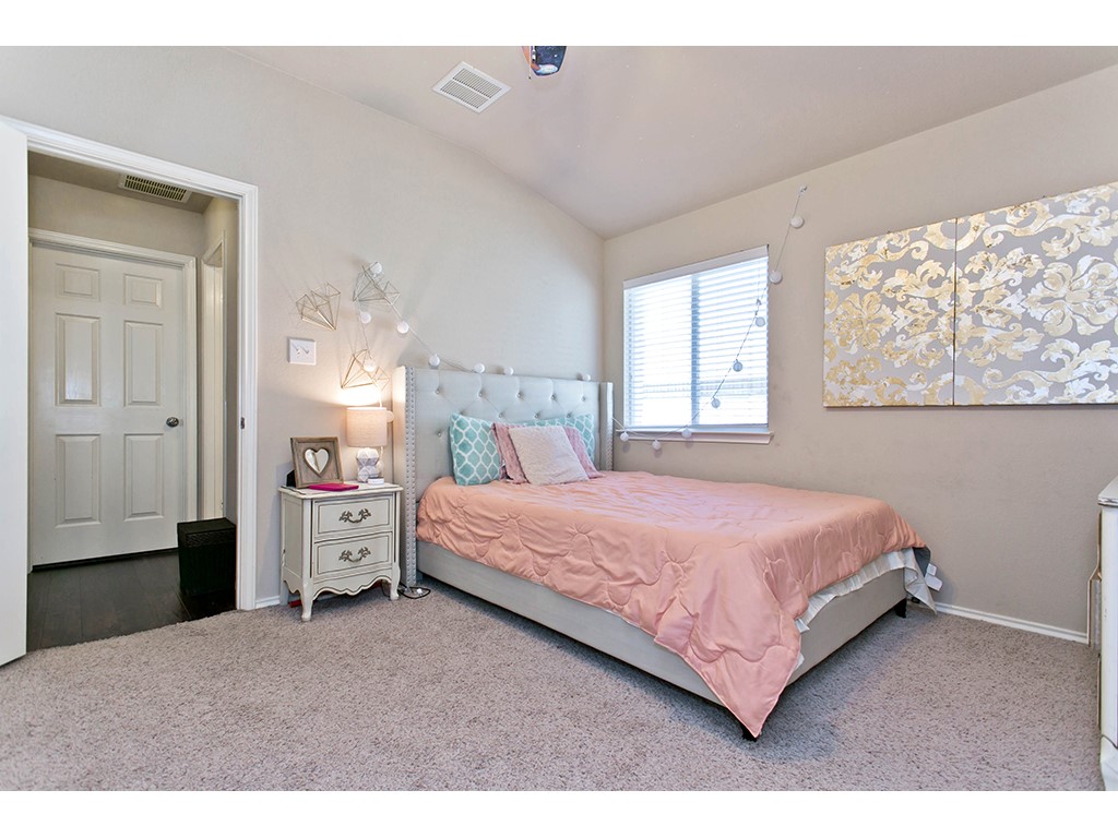 1808 Sand Creek Road Cedar Park, TX 78613 - Photo 15 of 25 Carpeted room with a vaulted ceiling, featuring a window with horizontal blinds, a six-panel interior door, and light neutral wall paint