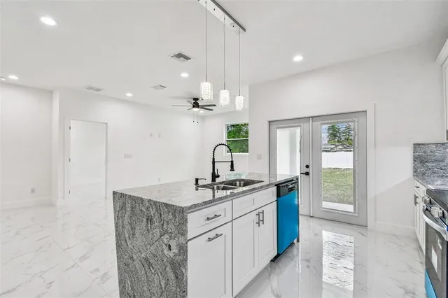 a kitchen with kitchen island granite countertop a sink cabinets and window
