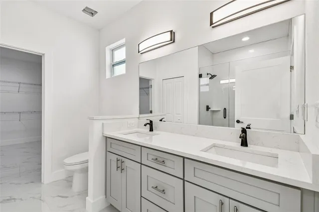 a bathroom with a sink a toilet and a large mirror