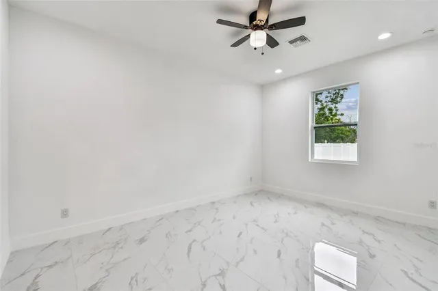 an empty room with a chandelier fan and windows