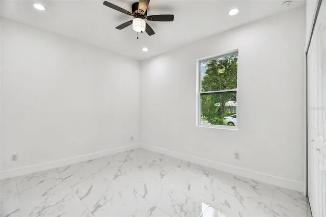 an empty room with a window and a ceiling fan