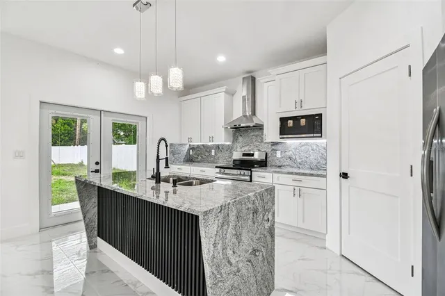 a kitchen with kitchen island granite countertop a sink a counter top space cabinets and stainless steel appliances