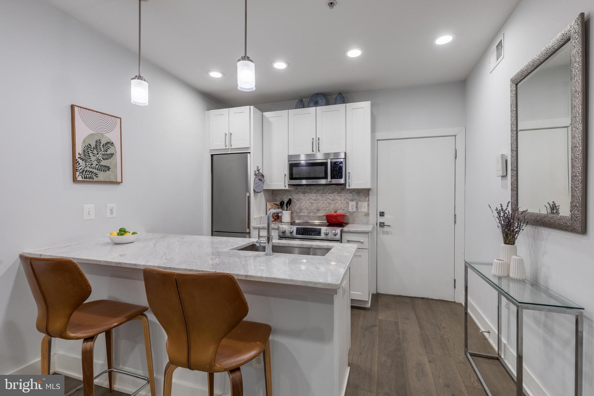 1412 Chapin Street Northwest, Unit 5 Washington, DC 20009 - Photo 3 of 23 a kitchen with stainless steel appliances granite countertop a refrigerator a sink dishwasher a stove with white cabinets and wooden floor