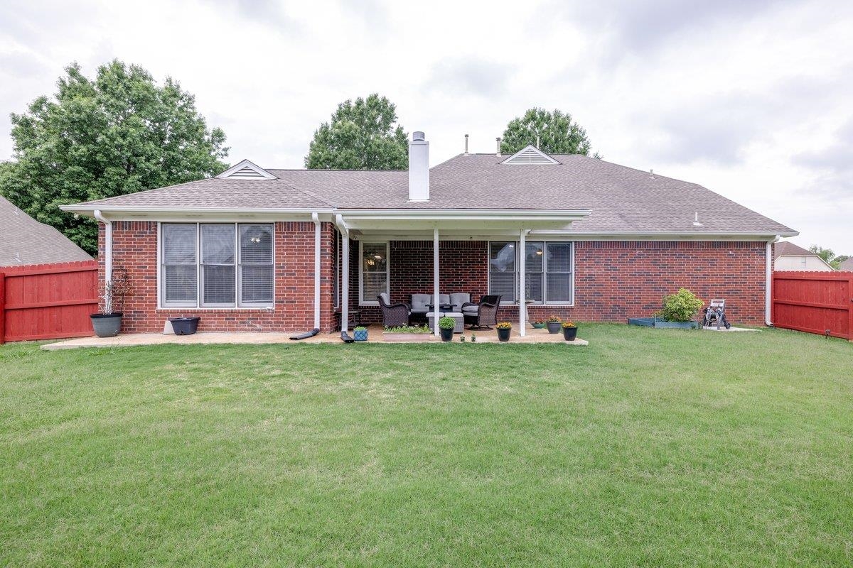 4840 Rainy Pass Road Collierville, TN 38017 - Photo 28 of 30 Expansive backyard featuring a manicured lawn, brick exterior, covered patio, additional patio space, and a red privacy fence
