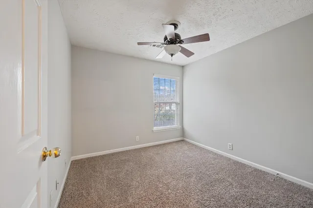 an empty room with windows and fan