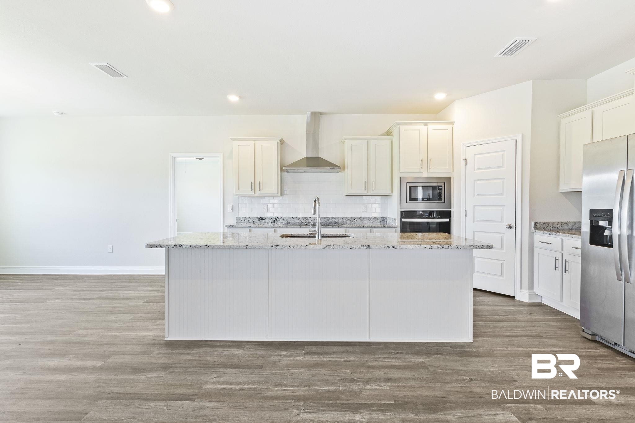 11303 Genuine Risk Circle Daphne, AL 36526 - Photo 21 of 100 Kitchen with sink, stainless steel appliances, wall chimney range hood, and an island with sink
