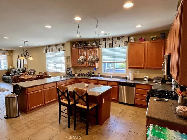 a kitchen with stainless steel appliances granite countertop wooden cabinets a sink a stove a dining table and chairs