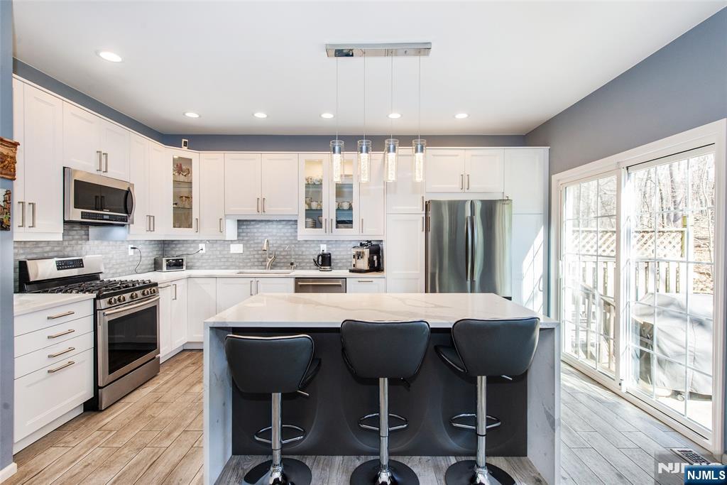 10 Gannet Court Wayne, NJ 07470 - Photo 1 of 24 a kitchen with stainless steel appliances granite countertop a stove a sink a refrigerator with a dining table and chairs