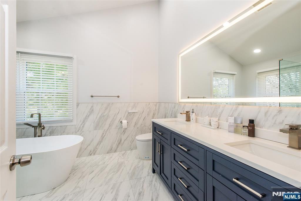 10 Gannet Court Wayne, NJ 07470 - Photo 15 of 24 a bathroom with a double vanity sink a mirror and a bathtub
