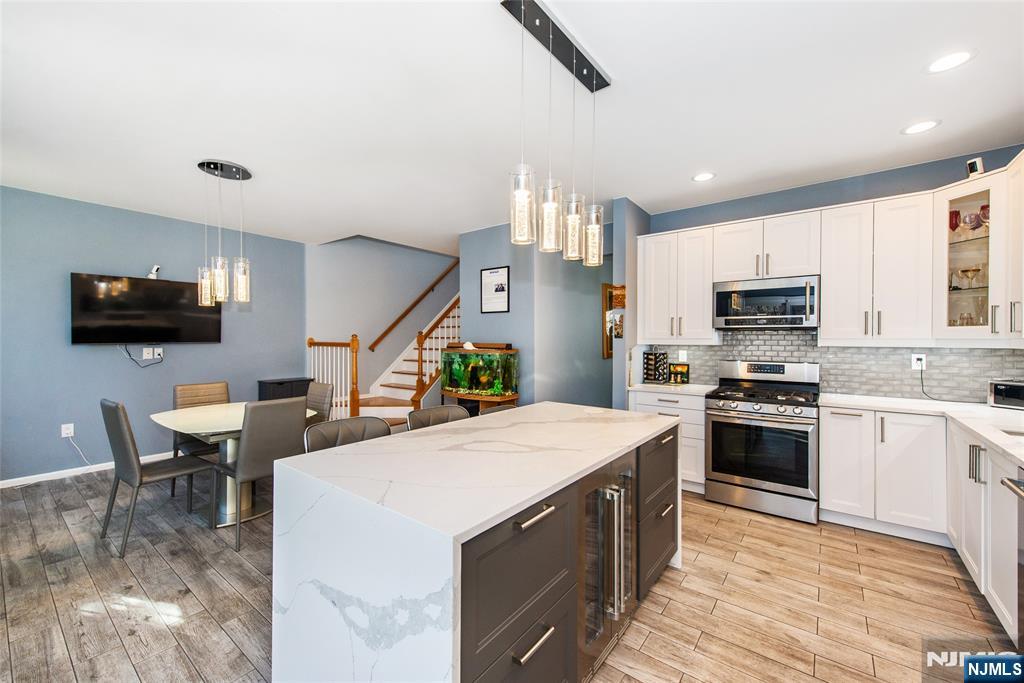 10 Gannet Court Wayne, NJ 07470 - Photo 2 of 24 a kitchen with stainless steel appliances granite countertop a stove top oven a sink dishwasher a dining table and chairs with wooden floor