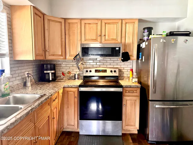 a kitchen with stainless steel appliances granite countertop a refrigerator a stove a sink and a microwave