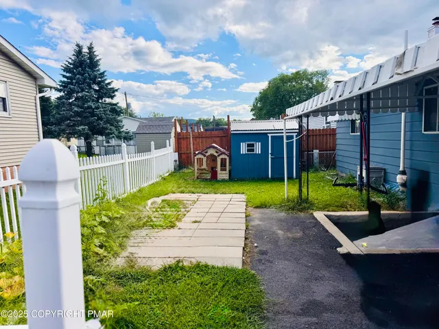 a view of a garden with a bench in front of house