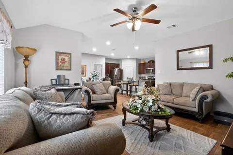 a living room with furniture kitchen view and a chandelier