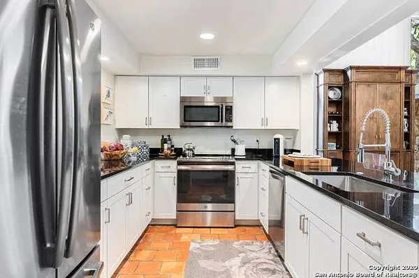 a kitchen with granite countertop a refrigerator stove and sink