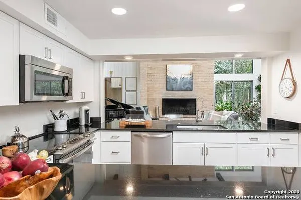 a kitchen with stainless steel appliances kitchen island granite countertop a stove a sink and a granite counter tops with white cabinets