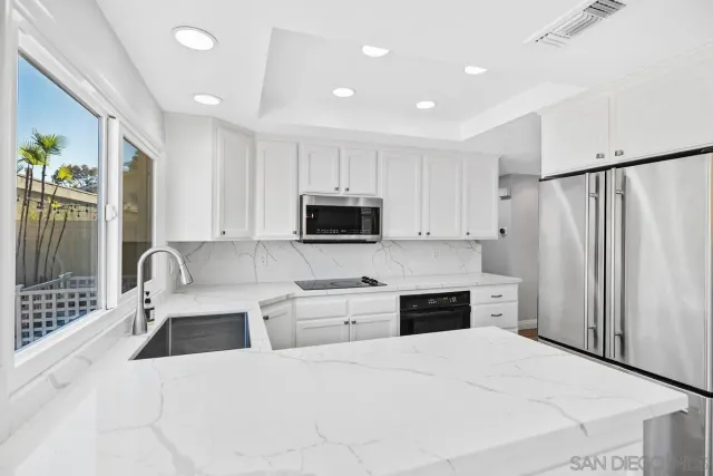 a large white kitchen with stainless steel appliances granite countertop a refrigerator stove microwave and sink