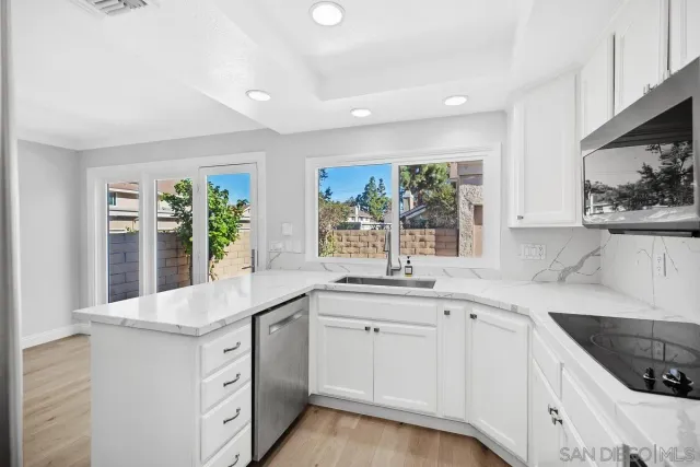 a kitchen with granite countertop white cabinets white appliances and a wide window