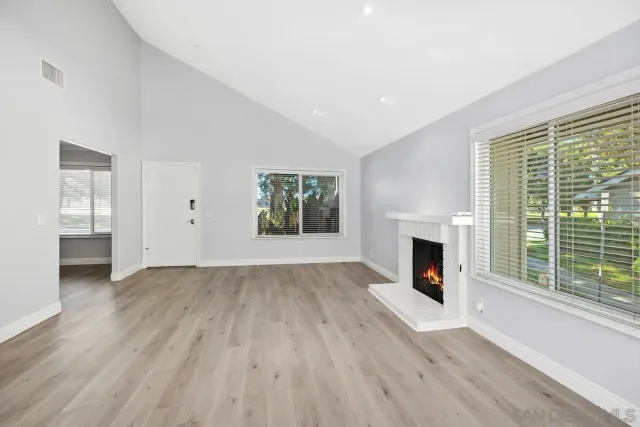 a view of empty room with wooden floor and fireplace
