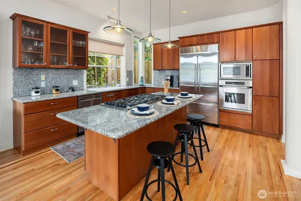 a kitchen with stainless steel appliances granite countertop wooden floor a stove a sink dishwasher and cabinets with wooden floor