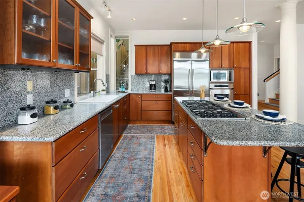 a large kitchen with stainless steel appliances granite countertop a stove a sink and a microwave