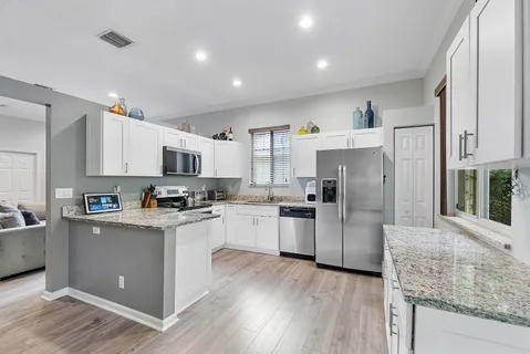 a kitchen with stainless steel appliances granite countertop a refrigerator a stove top oven a sink and dishwasher with wooden floor