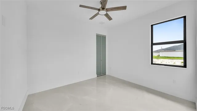 an empty room with a window and a ceiling fan