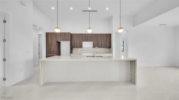 a large white kitchen with a large island oven a stove and a sink