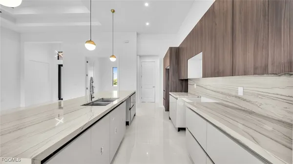 a large white kitchen with a large counter top a sink a stove and a refrigerator