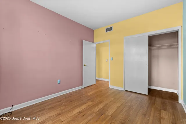 a view of an empty room with wooden floor and closet