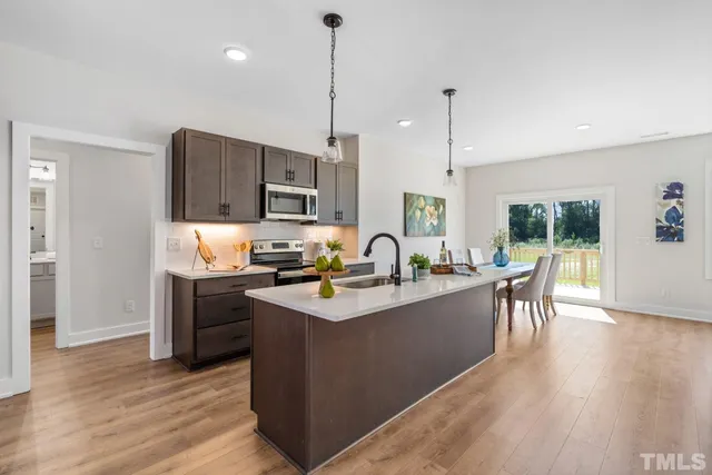 a kitchen with stainless steel appliances granite countertop a sink a stove a refrigerator a center island with wooden floor and cabinets