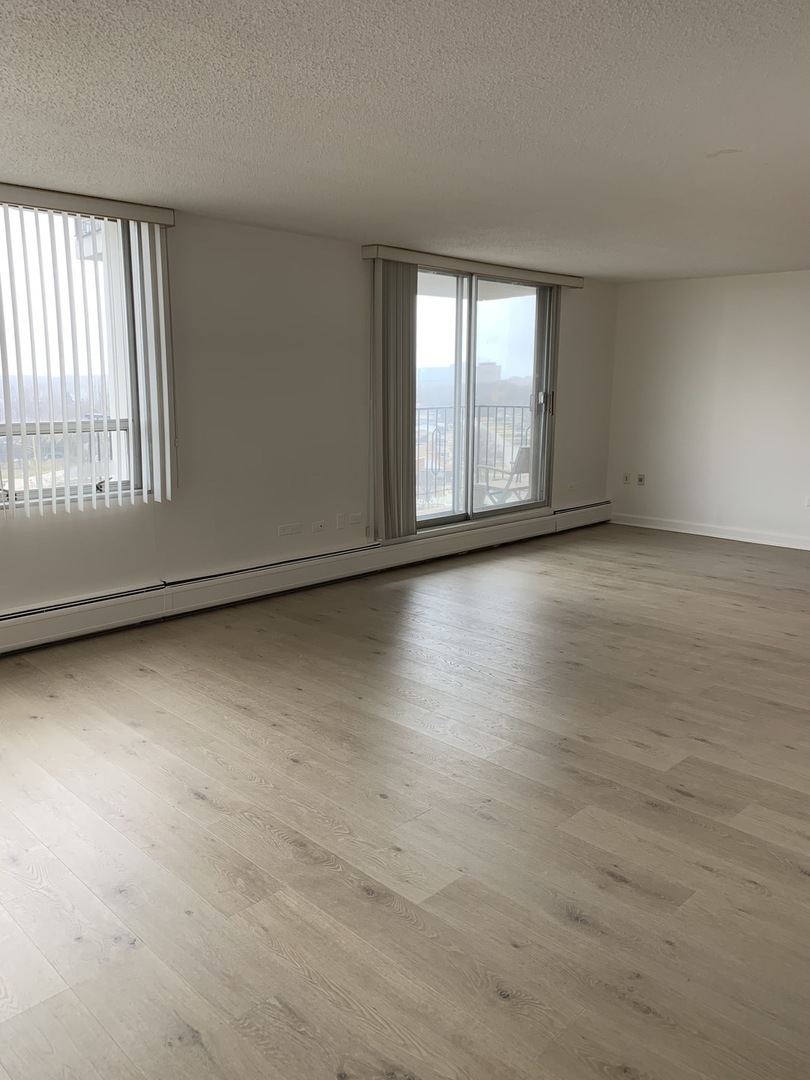 8809 Golf Road, Unit 8A Niles, IL 60714 - Photo 3 of 12 an empty room with wooden floor and windows