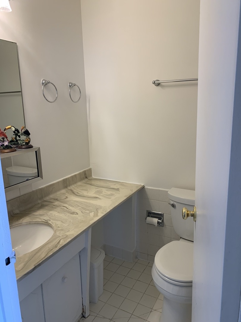 8809 Golf Road, Unit 8A Niles, IL 60714 - Photo 10 of 12 a bathroom with a granite countertop sink toilet and a mirror