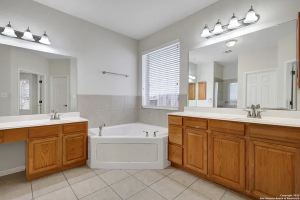 a bathroom with a double vanity sink a mirror a bathtub and window