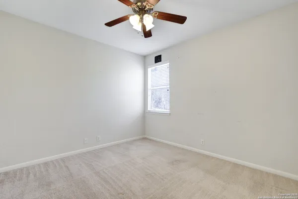 an empty room with a window and a fan