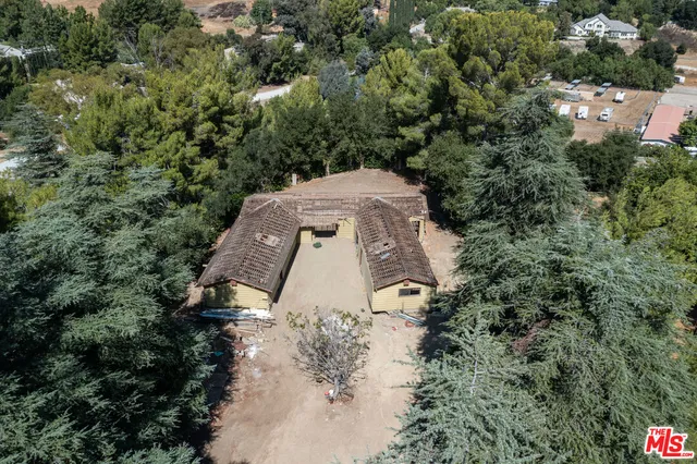 an aerial view of a house with a yard and trees all around
