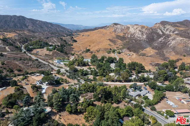 an aerial view of residential houses with outdoor space and trees