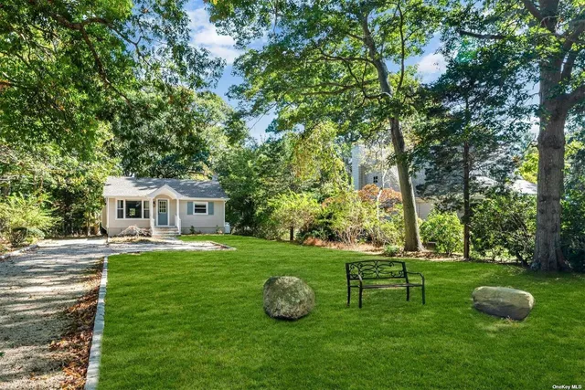 a front view of a house with garden and trees