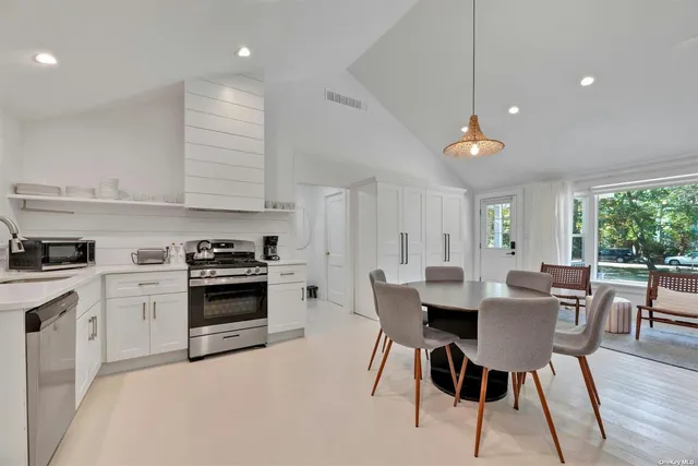 a kitchen with stainless steel appliances a table chairs and a refrigerator