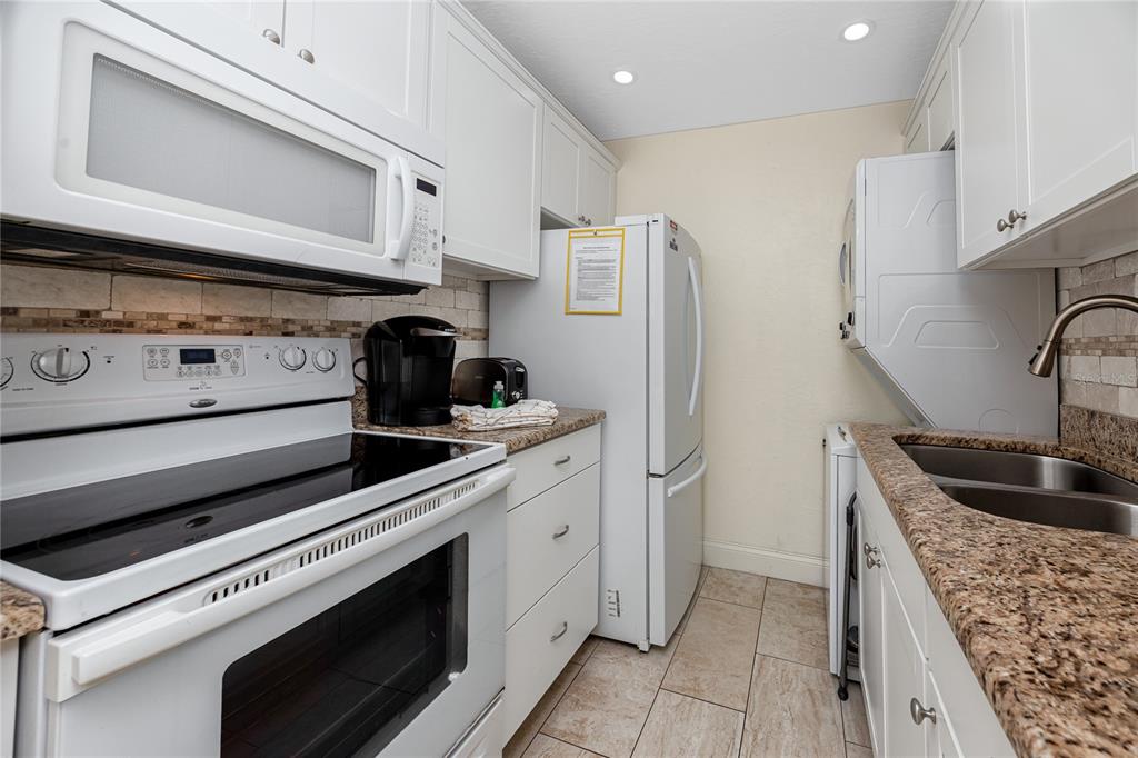 159 Medallion Boulevard, Unit F Madeira Beach, FL 33708 - Photo 18 of 47 a kitchen with stainless steel appliances kitchen island a stove and a refrigerator