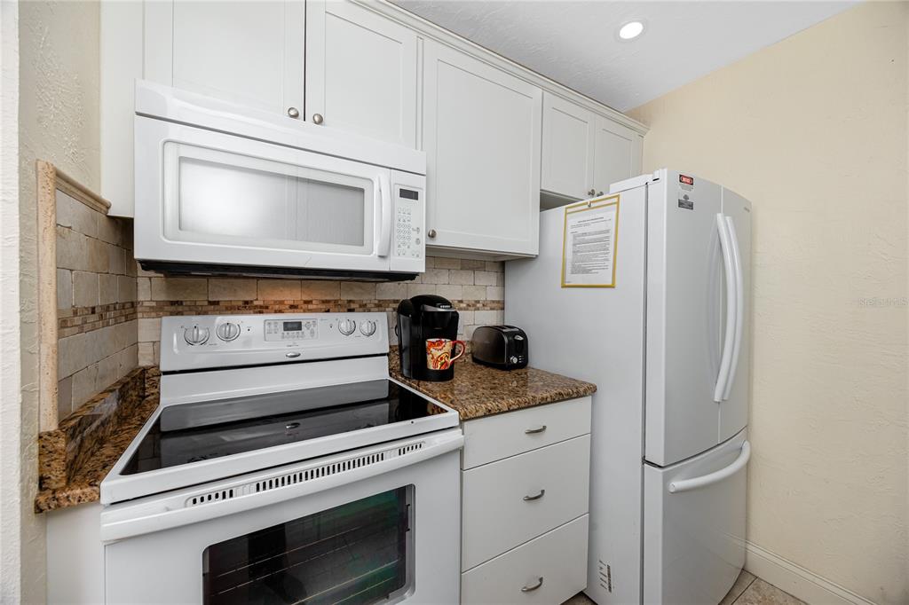 159 Medallion Boulevard, Unit F Madeira Beach, FL 33708 - Photo 19 of 47 a kitchen with stainless steel appliances white cabinets and a refrigerator
