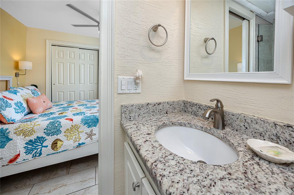 159 Medallion Boulevard, Unit F Madeira Beach, FL 33708 - Photo 27 of 47 a bathroom with a granite countertop sink and a mirror