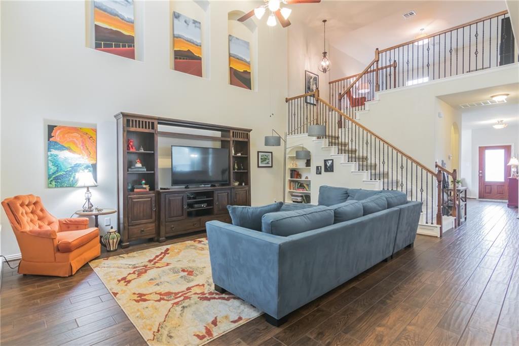 252 Pond View Pass Buda, TX 78610 - Photo 10 of 37 Living area featuring a towering ceiling, dark wood-type flooring, a ceiling fan, and stairs