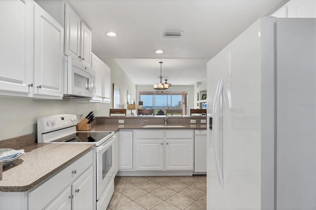 13313 Gasparilla Road, Unit 202 Placida, FL 33946 - Photo 16 of 57 a kitchen with a sink dishwasher and white cabinets with wooden floor
