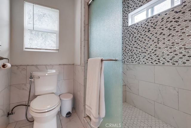 a white toilet sitting next to a bathroom sink and a shower