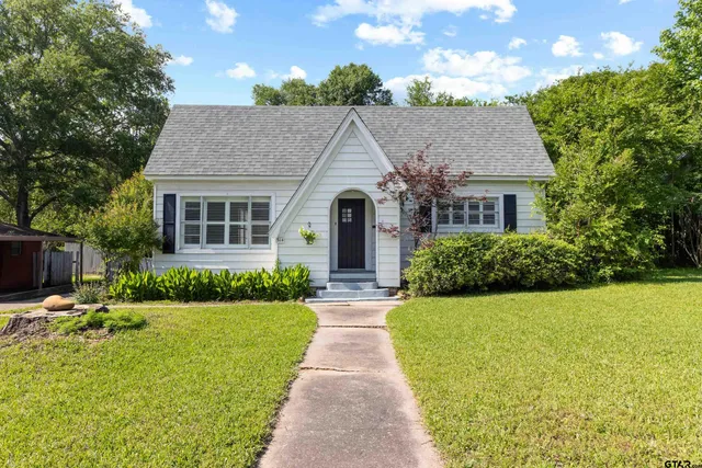 a view of house with garden and tall trees